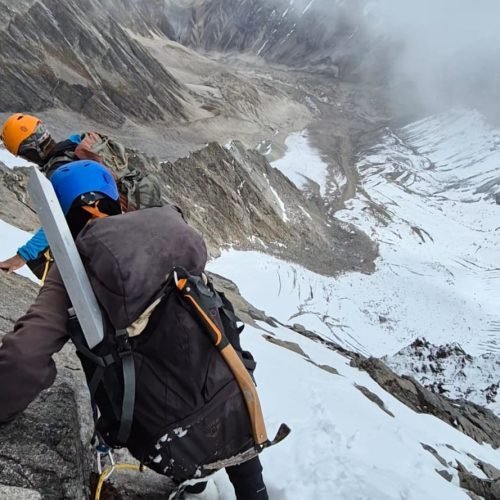 Climbers in helmets moving above a steep snowy slope